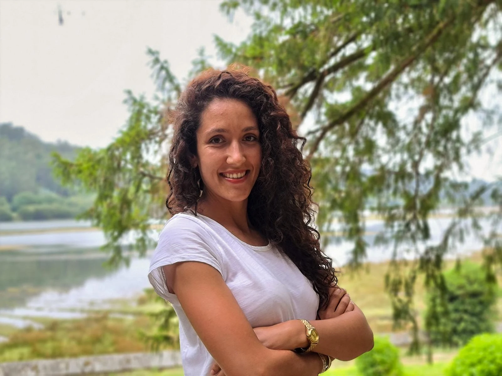Helena smiling beside a lake, surrounded by trees